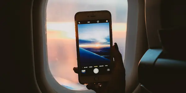 Το χέρι ενός ατόμου που κρατά ένα κινητό μέσα στο αεροπλάνο.