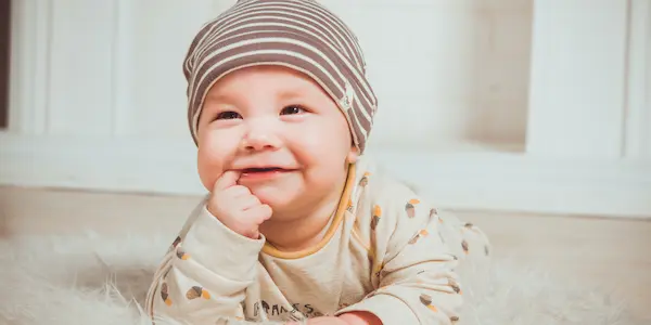 Χαμογελαστό μωρό που δαγκώνει το δεξί δείκτη.